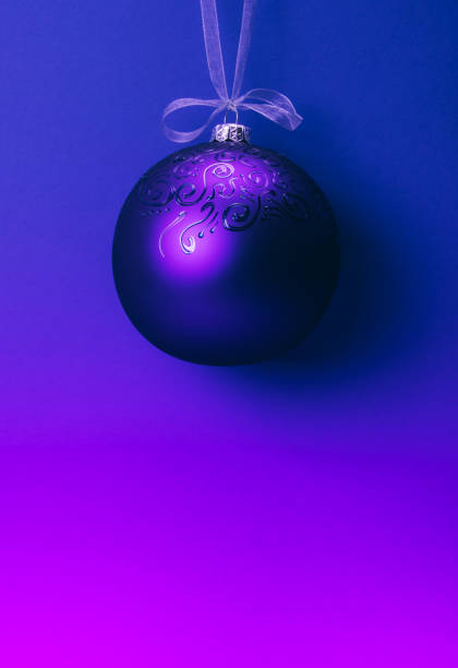 Creative neon colored gradient Christmas ball hanging on  a ribbon.  Christmas and New Year winter holidays greeting card.  Trendy colors background.   Place for text.