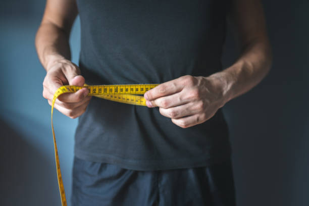Slim man measuring his waist. Healthy lifestyle, body slimming, weight loss concept. stock photo
