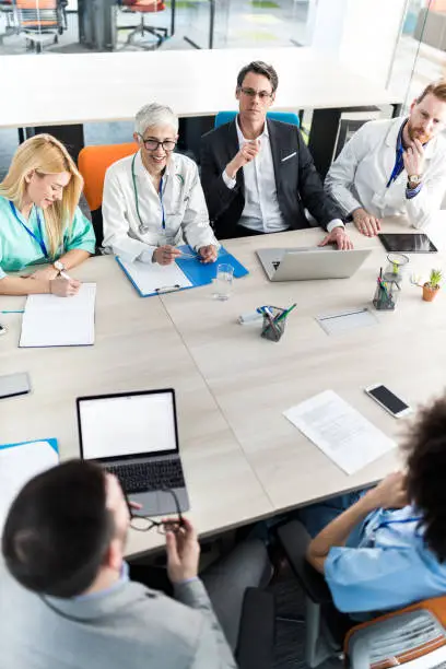 Photo of Above view of businessmen having a meeting with team of doctors in the office.