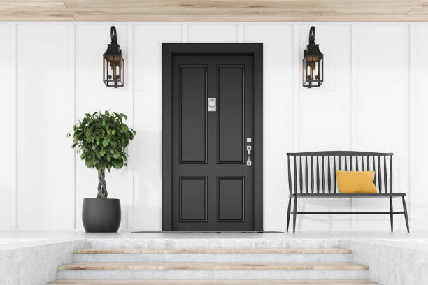 istock Black front door of white house, tree and bench 1191253317