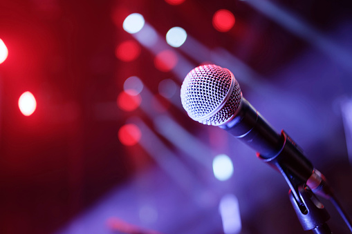 Dynamic microphone on stage in front of a large crowd in a theater.