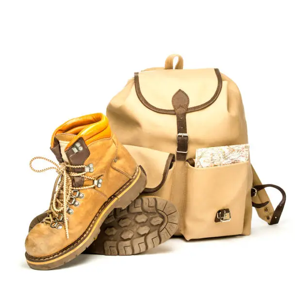 Vintage hiking boots, a vintage backpack made of canvas and an old map. Isolated on white, studio shot.