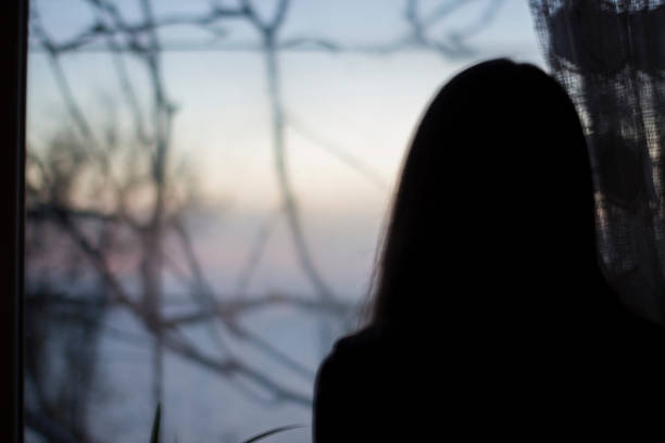 silhouette girl on dark window in house - depression, danger, blur - depression women sadness window imagens e fotografias de stock