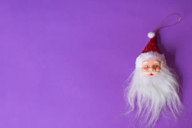 Santa Claus head positioned on the right side of a violet background. There is a lot of copy space available for text.