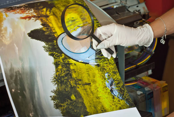 la ragazza con una camicia bianca stampa una foto. donna che guarda attraverso la foto con lente d'ingrandimento. l'assistente controlla l'immagine stampata. natura, verde e tenda nella foto. - photobusiness foto e immagini stock