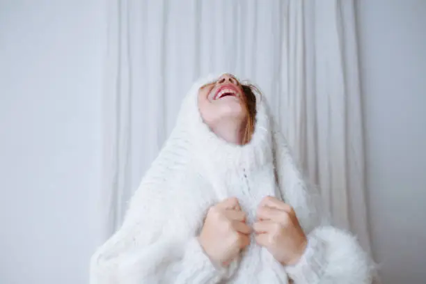 Photo of Funny little girl trying to squeeze her head through the collar of a sweater