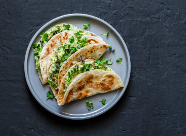 istock Avocado eggs greens salad paratha flatbread quesadilla on a dark background, top view 1191259031