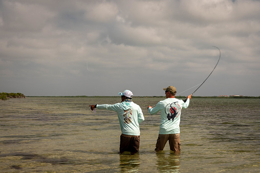Ambergris Caye, Belize - November, 16, 2019. A Belizean fishing guide pointing out  the school of bonefish on the flats on the small Caribbean island.