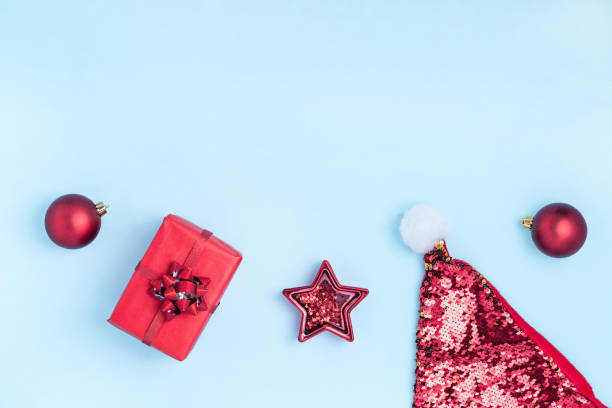 istock New Year and Christmas composition. Frame from red balls, red star, gift boxes, Santa's hat and sparkles on pastel blue background. Top view, flat lay, copy space 1191267934