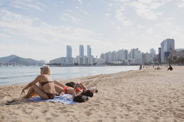 Busan, South Korea - September 18, 2019: As summer comes to an end, two Korean women take advantage of a warm afternoon to sunbathe at Gwangalli Beach in Busan, South Korea