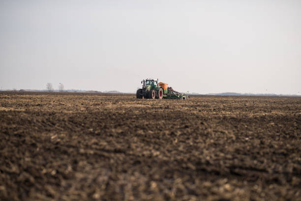 istock Farmer with tractor seeding, sowing crops at agricultural fields 1191270410