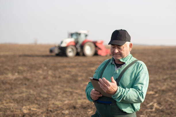 современный старший фермер с помощью планшета на поле - farmer laptop selling internet стоковые фото и изображения