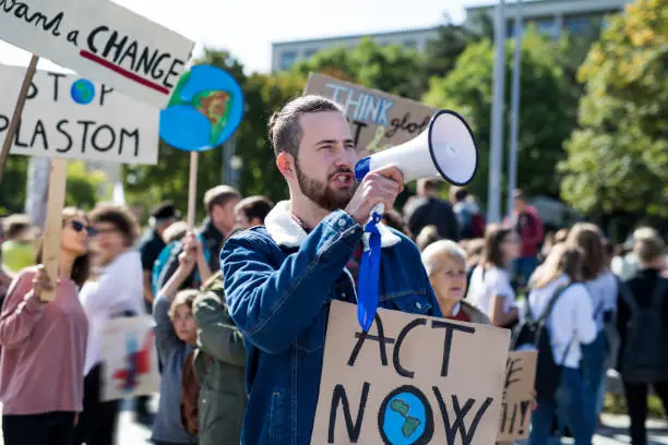 Photo of Man with placards and amplifier on global strike for climate change, shouting.