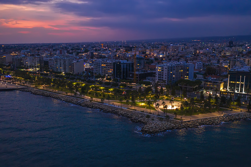 Aerial view of Limassol promenade or embankment with alley and buildings in Cyprus at night. Drone photo of mediterranean sea resort from above.