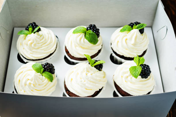 istock Chocolate cupcakes with blackberry and mint leaves in box for gift 1191273756