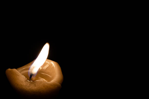 lonely memorial candle. Candle flame burns in dark stock photo