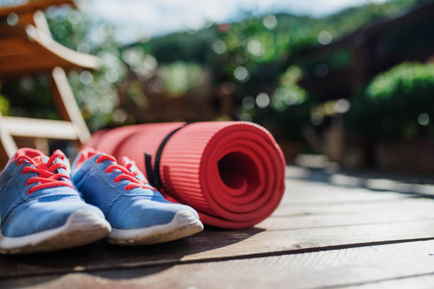 Exercise mat and trainers outdoors on a terrace in summer. Composition of exercise mat and trainers outdoors on a terrace in summer. exercise equipment stock pictures, royalty-free photos & images