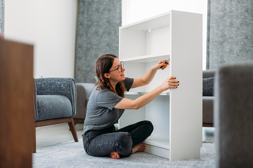 Woman Assembling Wooden Cabinet in Home