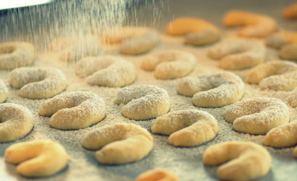 sprinkling powdered sugar on freshly baken vanilla crescents (vanillekipferl) - baking traditional culture studio shot horizontal imagens e fotografias de stock