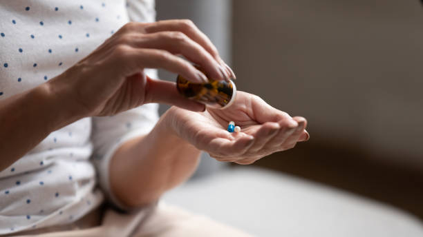 Close up view old woman holding bottle pouring out pills Close up 60s old woman pours out from bottle pills time to take medicaments, cure for memory loss, high blood pressure or cholesterol level remedy pain killer drugs, senile diseases treatments concept pharma herbal medicine pill medicine stock pictures, royalty-free photos & images