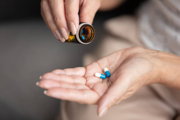 istock Closeup view elderly female holding two pills taking daily dosage 1191287565
