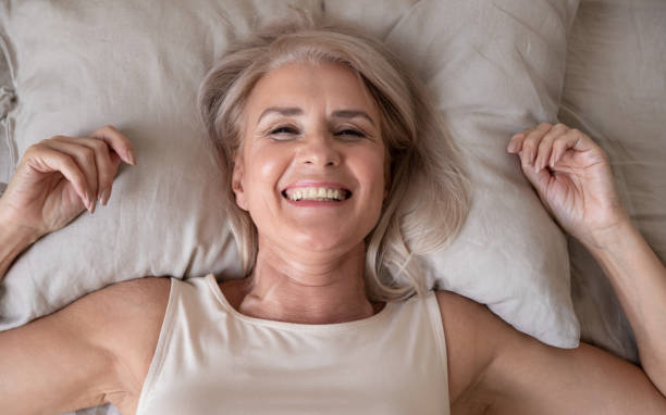 istock Happy refreshed elderly female lying in bed looking at camera 1191287596