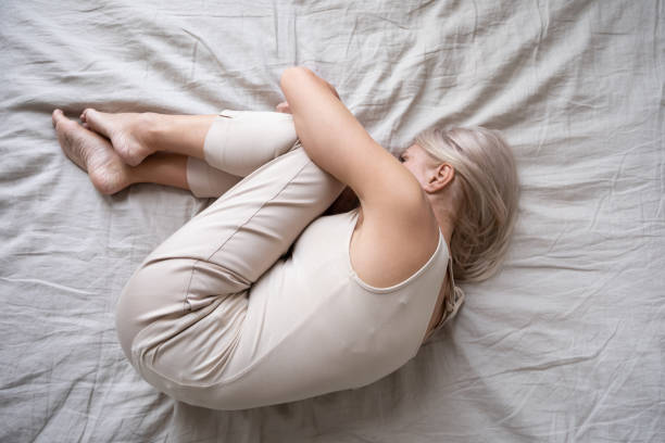 Top view depressed aged female lying in bed feels unhappy