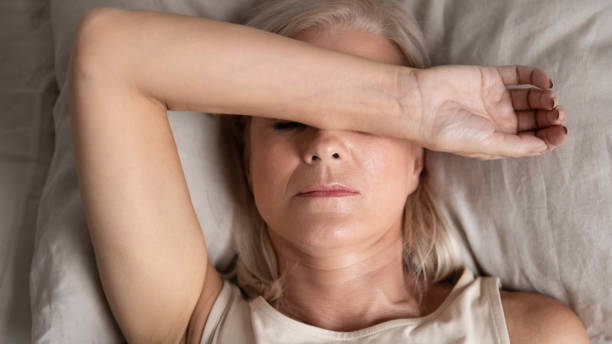 Closeup melancholic woman lying put hand on face feels unwell Close up top view middle-aged woman lying down in bed on pillow put hand on face, concept of female having insomnia sleeping disorder or migraine pain, melancholic mood, personal life troubles concept exhaustion stock pictures, royalty-free photos & images