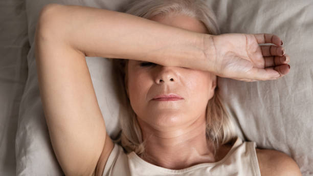 closeup melancholic woman lying put hand on face feels unwell - menopause imagens e fotografias de stock