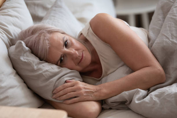 triste anciana acostada en la cama sufre de insomnio - pessimist women one person caucasian fotografías e imágenes de stock