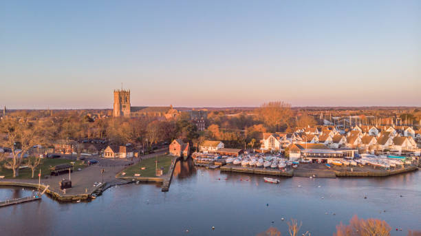 An aerial view of a river at golden hour with grassy bank and majestic church and marina in the background under a majestic blue sky An aerial view of a river at golden hour with grassy bank and majestic church and marina in the background under a majestic blue sky christchurch england photos stock pictures, royalty-free photos & images