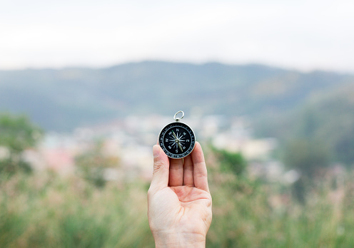 holding compass to orientate in a place with nature and mountains