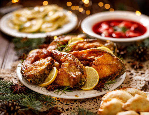 Fried carp fish slices on a ceramic plate on the holiday table, close up. Traditional christmas eve dish. Fried carp fish slices on a ceramic plate on the holiday table, close up. Traditional christmas eve dish. Polish Christmas carp stock pictures, royalty-free photos & images