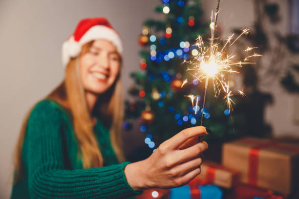 istock Woman holding sparkler next to Christmas tree 1191317084