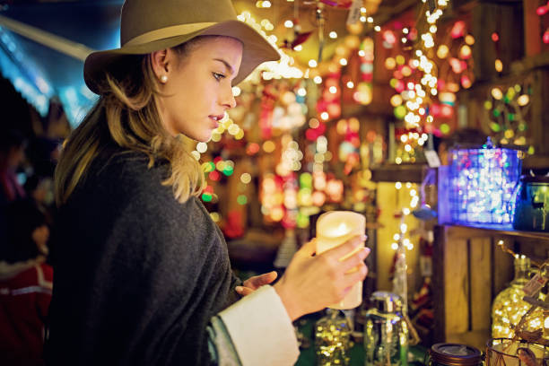 la jeune femme choisit des cadeaux et la décoration au marché de noel - bougie led photos et images de collection