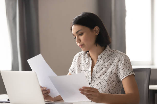 istock Serious Asian businesswoman reading documents, analyzing statistics 1191319743