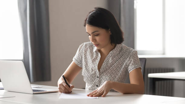 istock Focused Asian businesswoman signing paper document, writing notes 1191319747