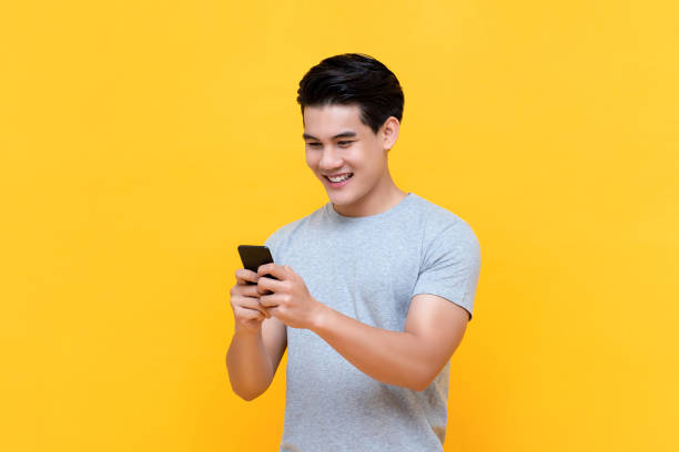 istock Handsome smiling young Asian man texting message on smartphone 1191327294