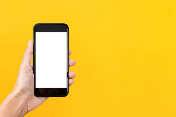 Hand holding mobile phone with empty screen Hand holding empty screen mobile phone isolated on yellow background with copy space demanding photos stock pictures, royalty-free photos & images
