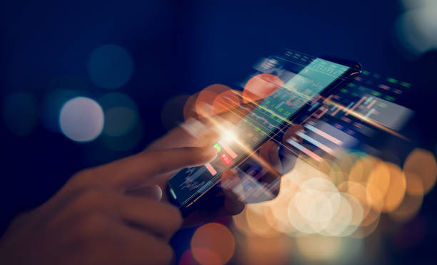 Stock exchange market concept, hand trader touching on smartphone with graphs analysis candle line on bokeh colors light in night atmospheric city. stock photo
