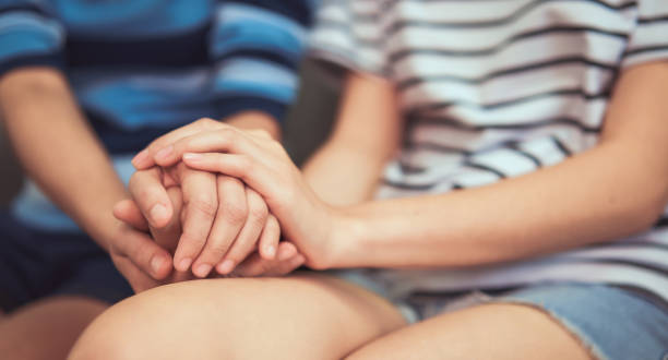 istock Two woman holding hands to encourage and help when suffering. 1191330373