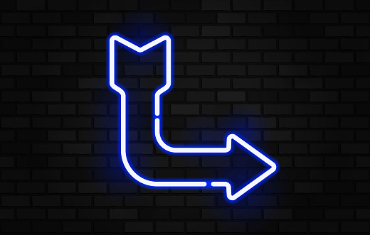 neon arrow sign on black brick wall night