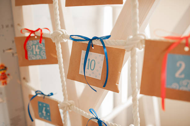 calendario de adviento, sobres artesanales con una cinta azul y pequeñas sorpresas en el interior con los números sobre un fondo blanco - advent calendar advent christmas childhood fotografías e imágenes de stock