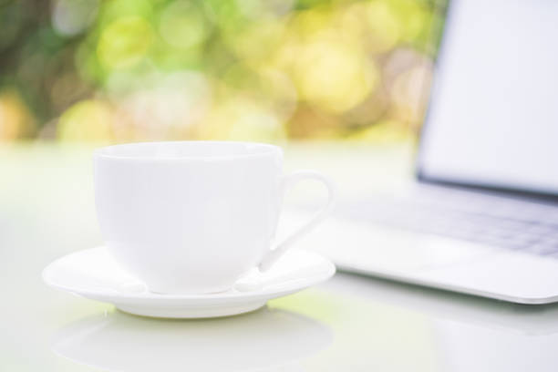 istock Close up coffee cup and laptop on table at office with bokeh 1191344417
