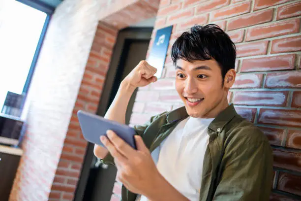 young man watch ballgame or play the mobile game on 5g smartphone with fist gesture happily