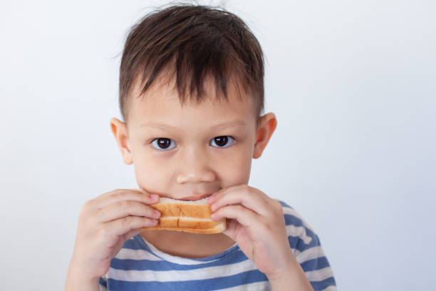 Asian little boy eating bread before go to school Asian little boy eating bread before go to school eating child cracker asia stock pictures, royalty-free photos & images