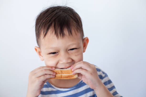 niño asiático comiendo pan antes de ir a la escuela - eating child cracker asia fotografías e imágenes de stock