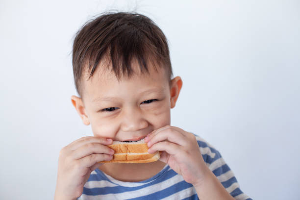 Asian little boy eating bread before go to school Asian little boy eating bread before go to school eating child cracker asia stock pictures, royalty-free photos & images