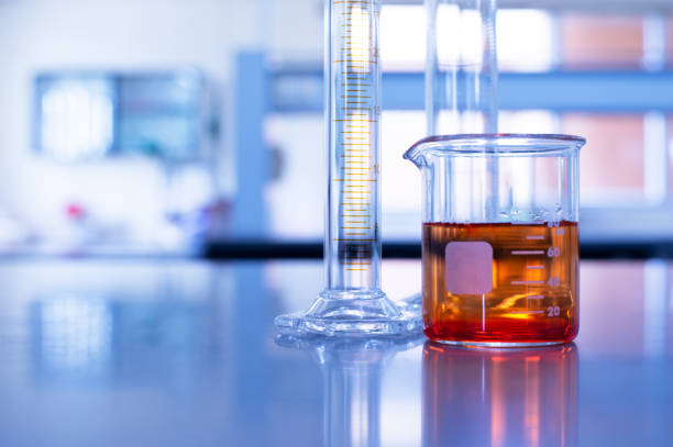 istock glass beaker with orange solution and cylinder in blue chemistry laboratory background 1191356201