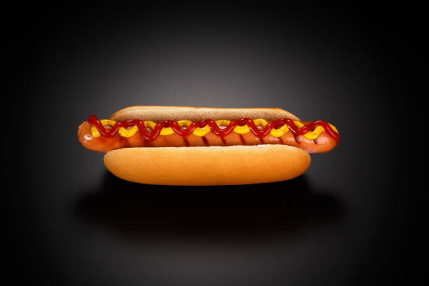 Classic hot dog with ketchup and mustard on a black background. stock photo